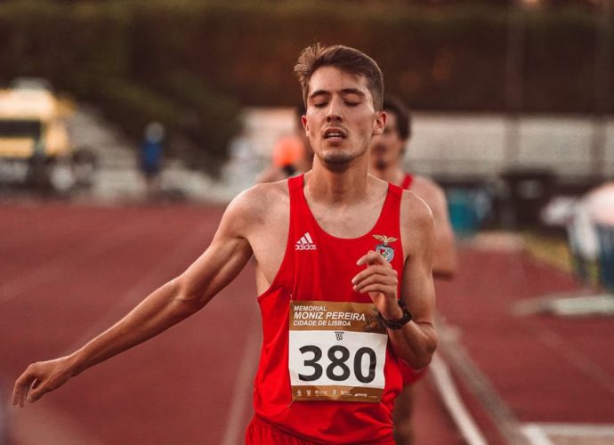 A young male runner crossing the finish line on a track, demonstrating determination and effort.