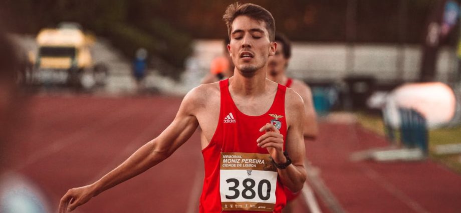 A young male runner crossing the finish line on a track, demonstrating determination and effort.